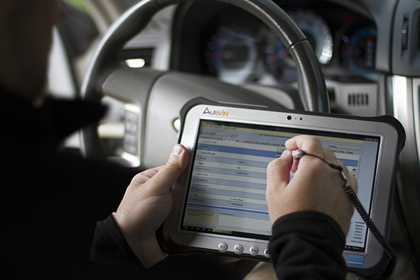 Image of a man entering information on a tablet inside a car.